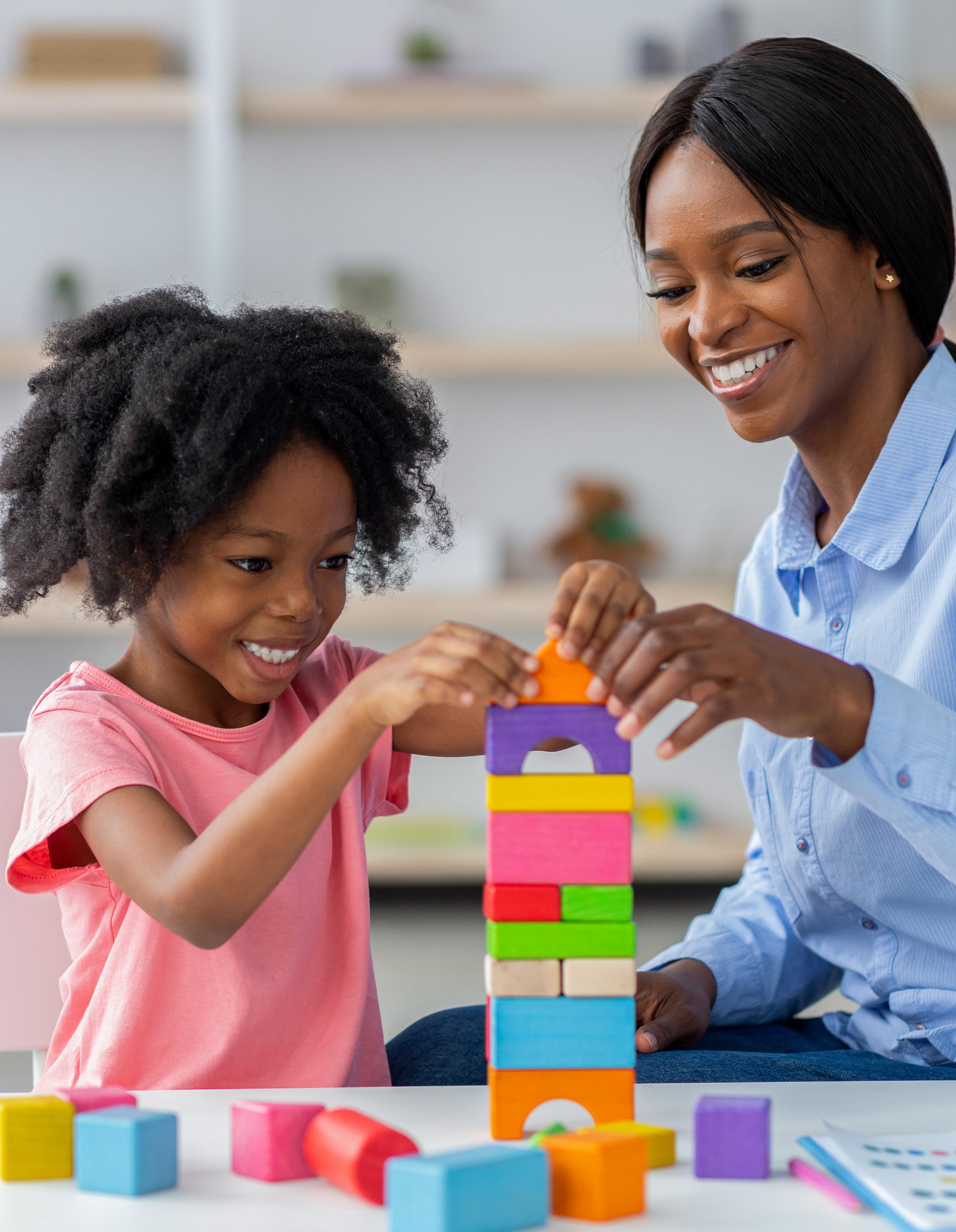 Therapist and child building colorful block tower during ABA session